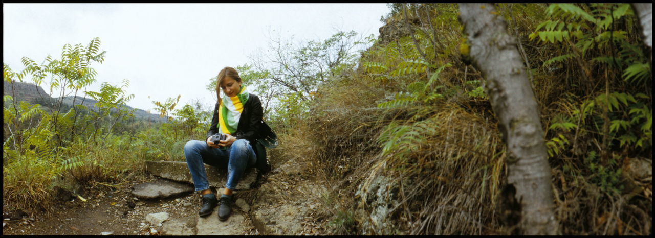 WOMAN SITTING ON TREE TRUNK