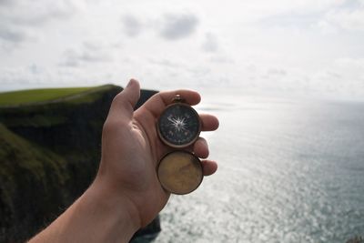 Cropped image of hand holding compass