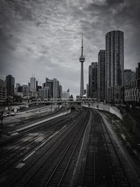 View of railroad tracks by buildings in city against sky