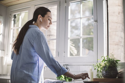 Side view of businesswoman using smart phone on kitchen counter at home office