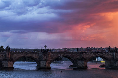 Arch bridge over river against cloudy sky