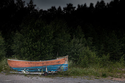Empty boat by trees in forest against sky