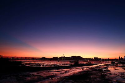 Bridge and sea against sky during sunset