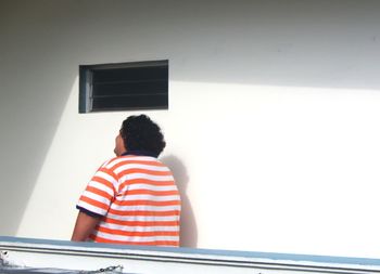 Rear view of boy standing against wall