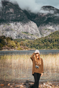 Woman shielding eyes while standing by lake