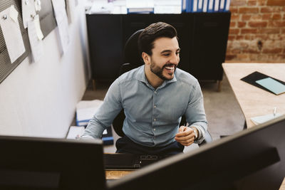 Cheerful business man sitting at desk while looking away