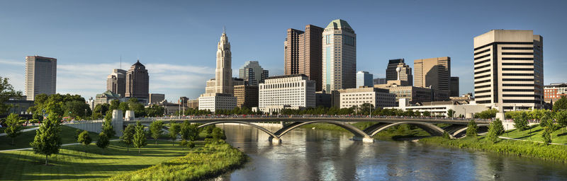 Bridge over river amidst buildings in city against sky