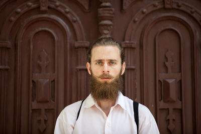 Portrait of young man standing against wall