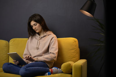 Young woman using phone while sitting on sofa
