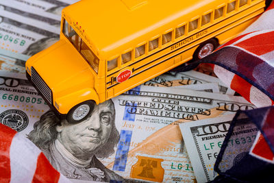 High angle view of figurine school bus on american flag and paper currency