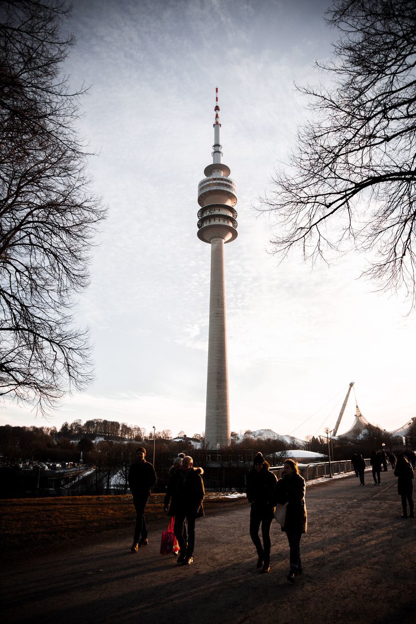 GROUP OF PEOPLE WALKING IN FRONT OF TOWER