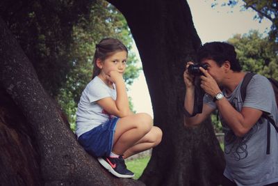 Young man photographing on tree trunk