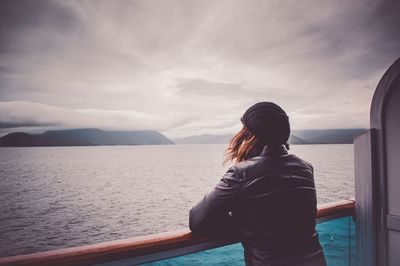 Woman looking at sea while leaning on railing in boat