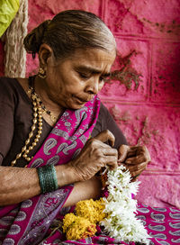 Midsection of woman holding flowers on wall