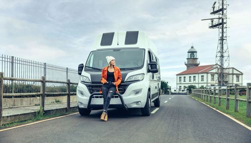 Woman leaning on camper van on the road