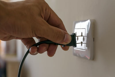 Cropped hand of person plugging electric switch