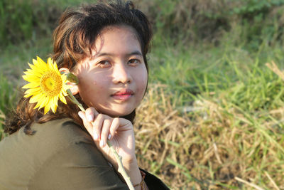 Close-up portrait of smiling woman with red flower