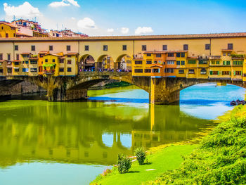 Arch bridge over river amidst buildings in city