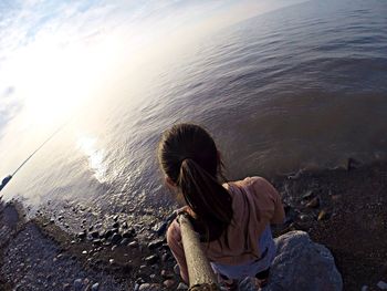 Rear view of woman standing at beach during sunset