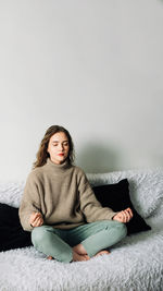 Portrait of young woman sitting on sofa at home