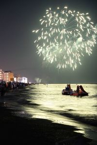 People in sea against sky at night