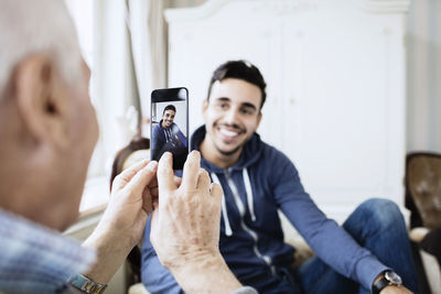 Senior man photographing caretaker through smart phone