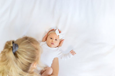 High angle view of woman holing baby boy in hand on bed at home