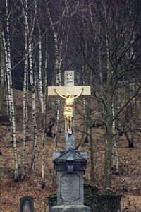 Statue of cross against trees