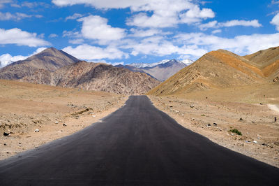 Road leading towards mountains against sky