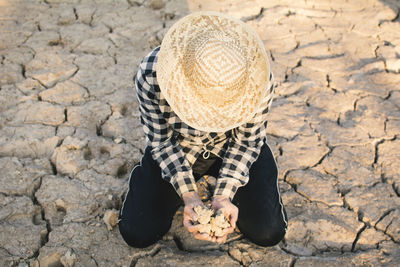 High angle view of man kneeling on barren land