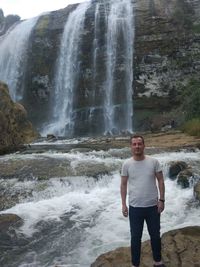 Full length of young man standing against rocks