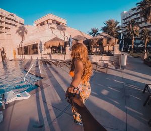 Woman standing by swimming pool against sky