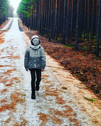 Person walking on road against trees during autumn