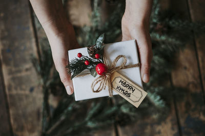 Cropped hands holding christmas present over hardwood floor