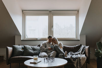 Female couple sitting together on sofa and looking at cell phone