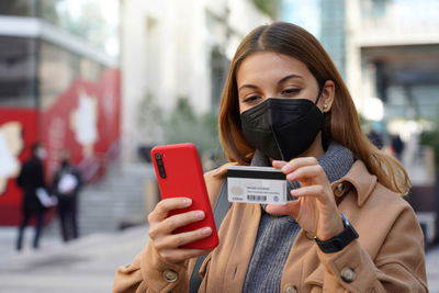 Close-up image of young woman using credit card for purchasing and shopping online on mobile phone