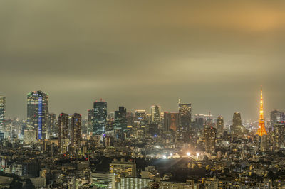 Illuminated buildings in city against sky