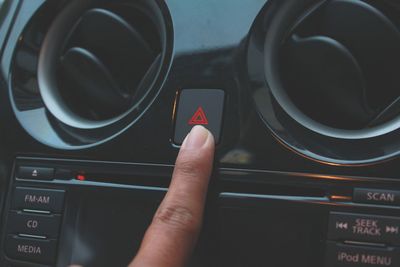 Cropped hand touching button in car