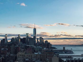 Distant view of one world trade center against sky during sunset in city