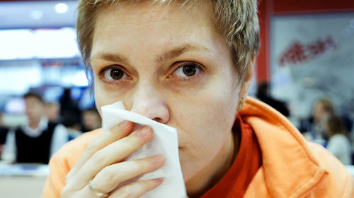 Close-up portrait of woman sneezing at restaurant