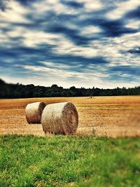 Hay bales on field against sky