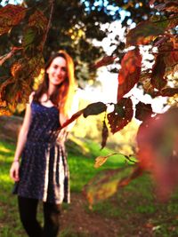 Portrait of young woman standing on tree