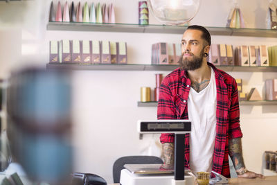 Male owner looking away while standing in candy store