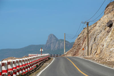 Road by mountain against clear blue sky