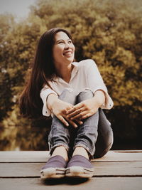 Smiling woman looking away while sitting on plank