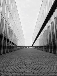 Footpath amidst modern buildings against sky in city