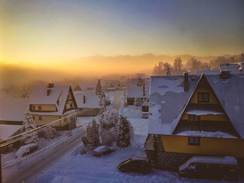 Snow covered landscape against sky during sunset