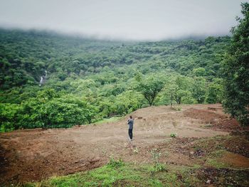 Rear view of man standing on field against sky