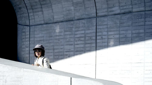 Portrait of teenage girl sitting on concrete wall