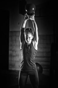 Young woman lifting exercise equipment at gym